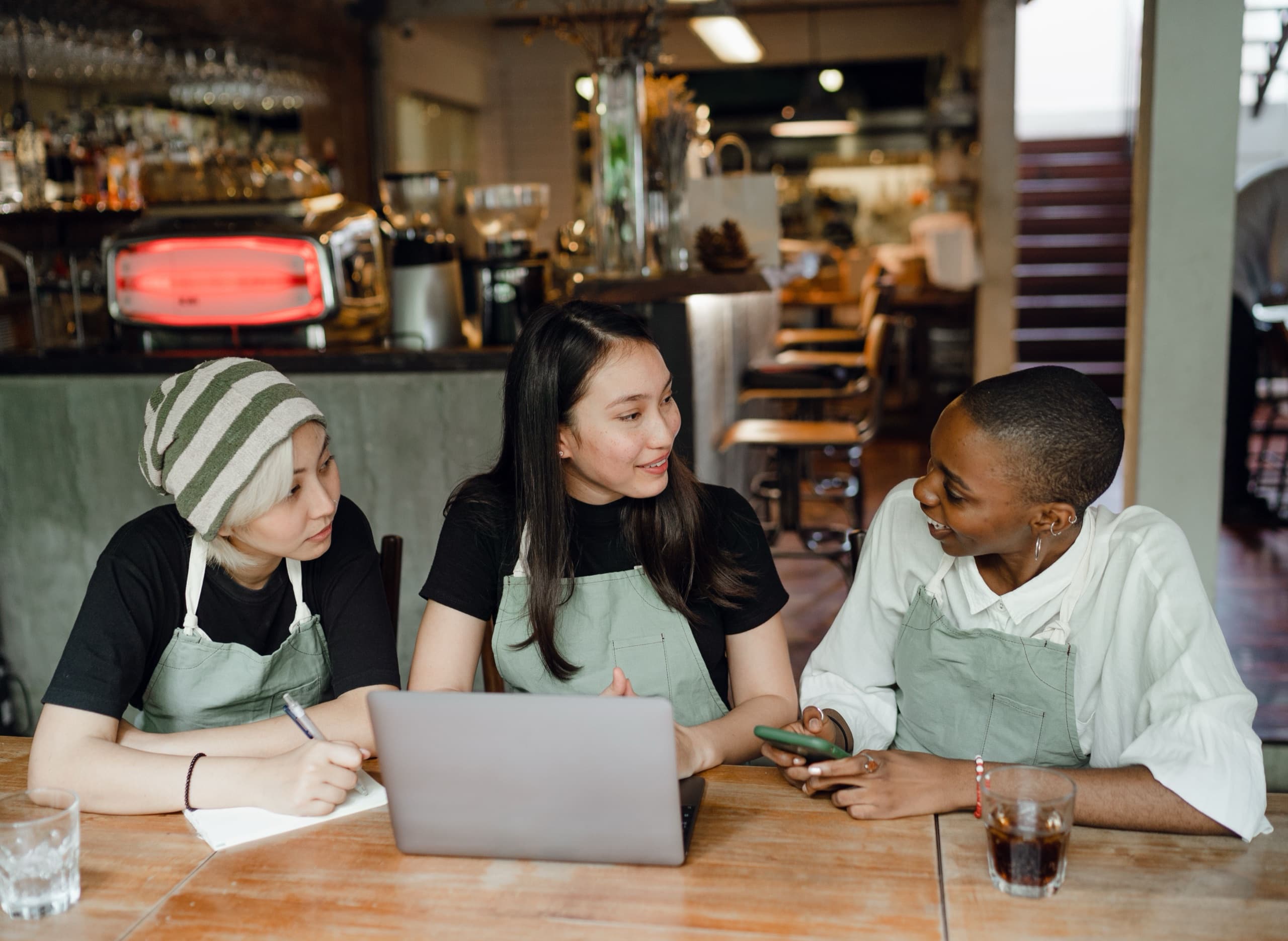 Three café owners going over their numbers on a laptop